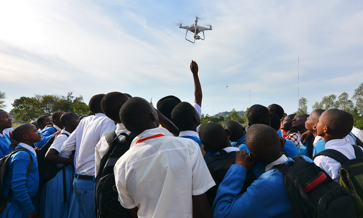Photo showing students looking up at flying drone.